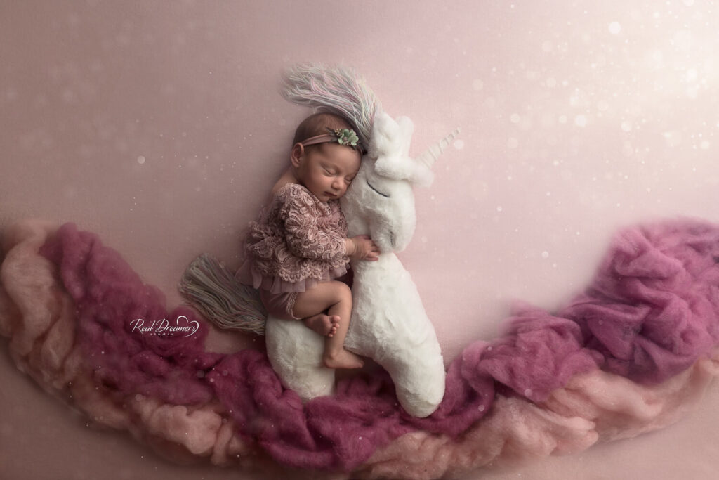 una bimba con vestitino di tulle dorme su un pupazzo di unicorno durante il servizio fotografico neonati